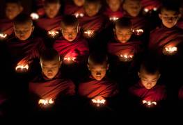 Jeunes moines bouddhistes priant à la lueur d'une bougie (Scott Stulberg) - Muzeo.com